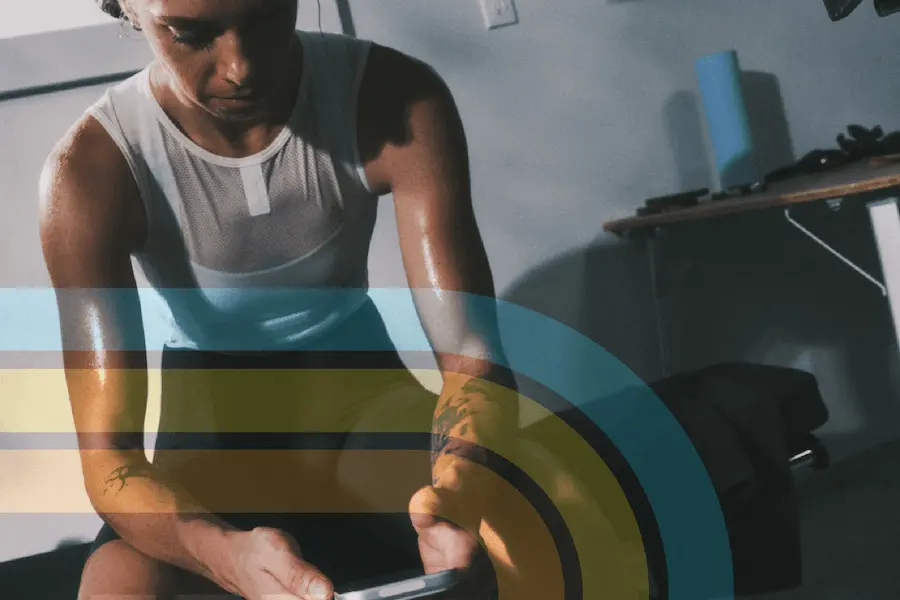 Athlete checking her training data on her phone after a workout in a home gym